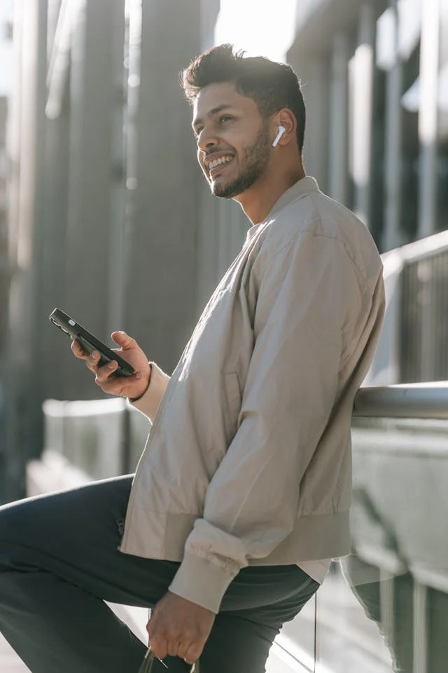 Man using a smartphone outdoors with a blurred background