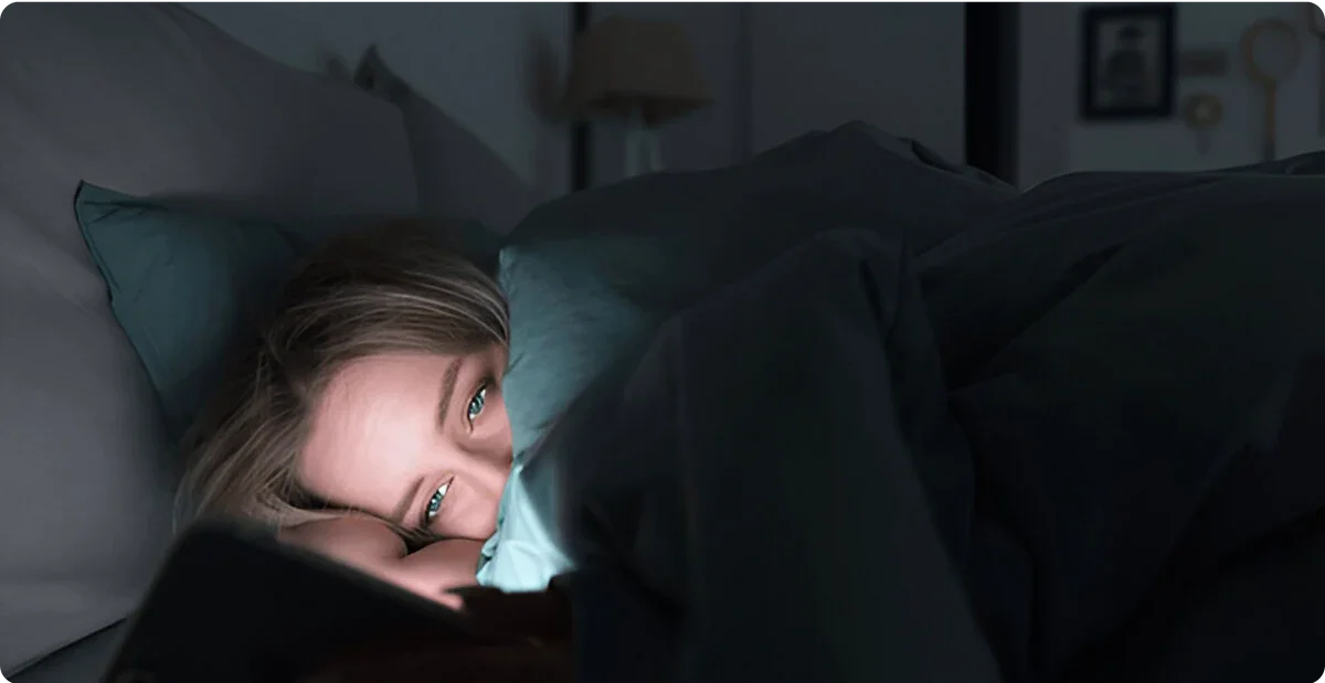 Person lying in bed using a smartphone in a dimly lit room