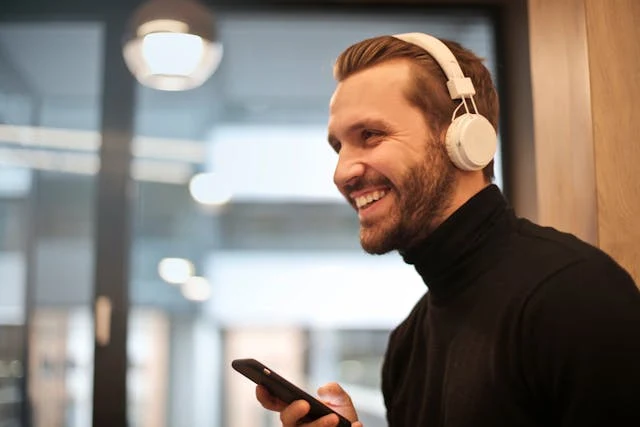 Man wearing headphones and using a smartphone indoors