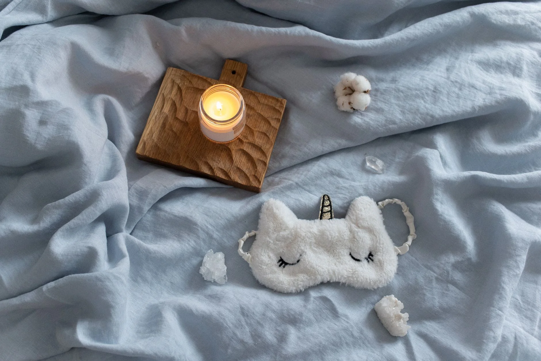 Cozy bedtime self-care setup with a candle and sleep mask — a relaxed starting point for choosing your first vibrator