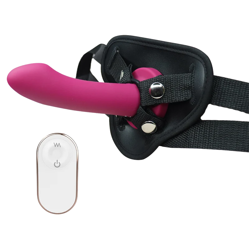 Pink silicone dildo with black harness and remote control on a white background