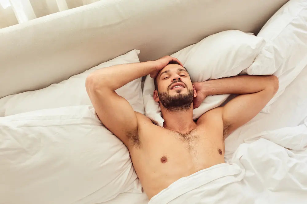 A woman lying peacefully in soft white sheets, her face showing bliss and satisfaction.