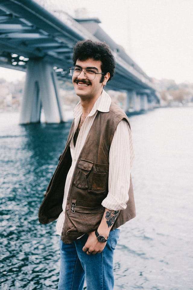 Man standing by a body of water with a bridge in the background