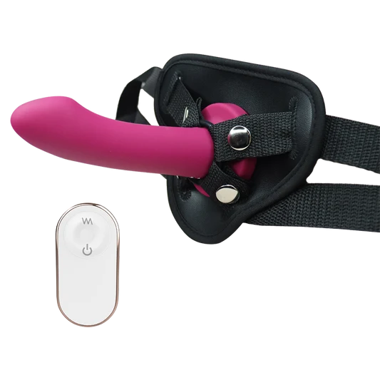Pink silicone dildo with black harness and remote control on a white background