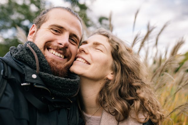 Man and woman embracing outdoors with a blurred natural background