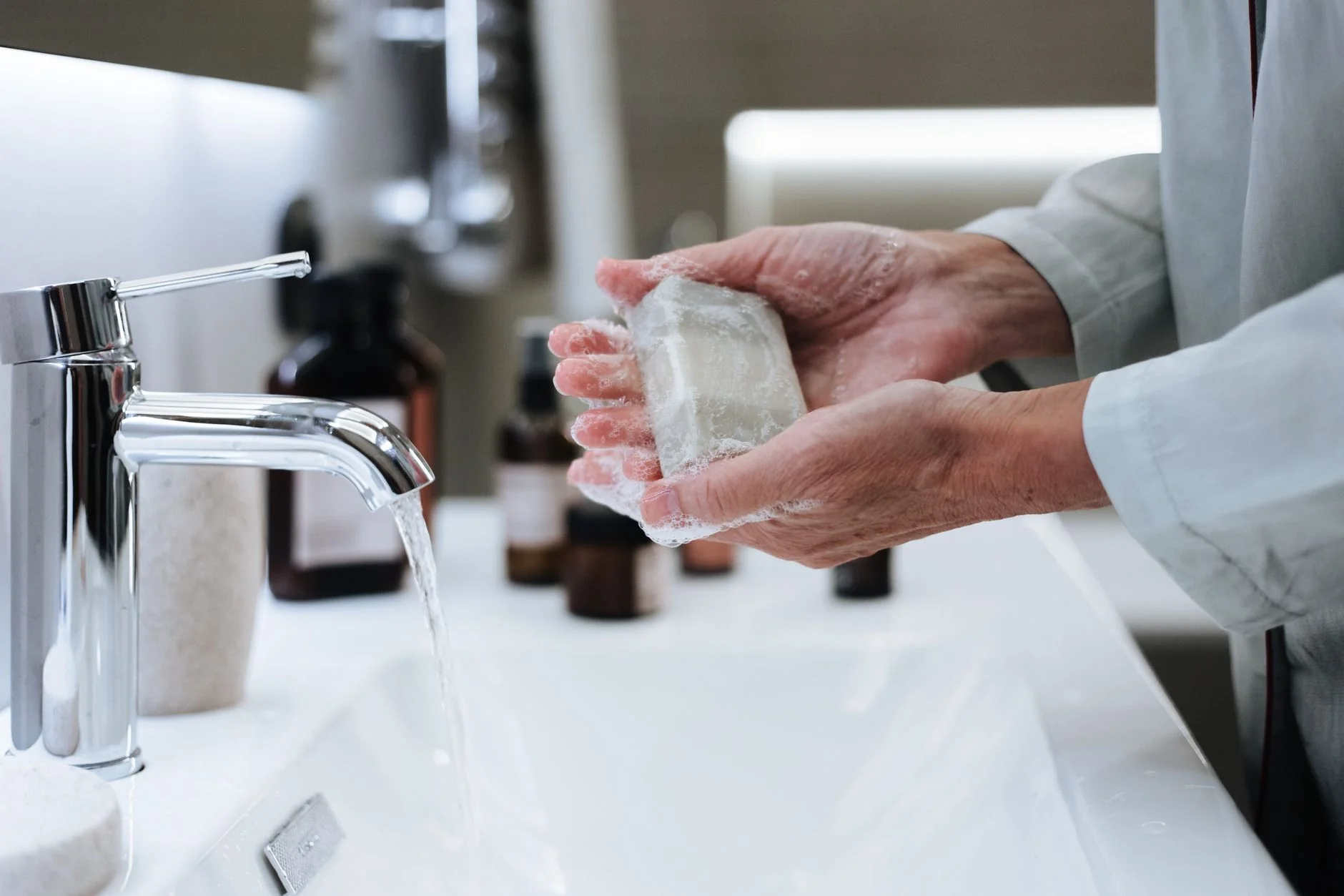 Hands washing with soap under running water — clean toys before and after every use
