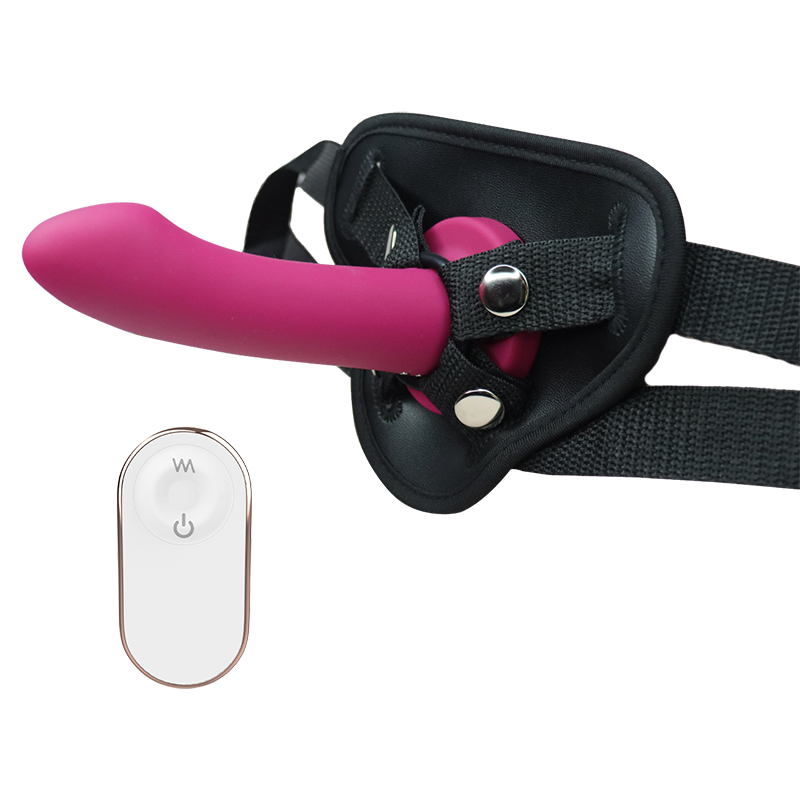 Pink silicone dildo with black harness and remote control on a white background
